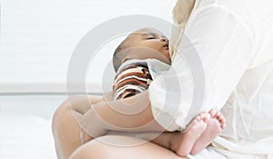 Portrait of Little cute African newborn baby is sleeping in mother`s arms with love at home. Childcare concept. White background.