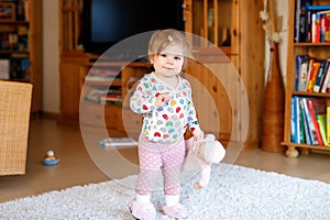 Portrait of little cute baby girl learning walking and standing. Adorable toddler girl at home