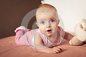 Portrait of a little cute baby lying on bed with his soft toy and smiling. crust on the baby`s head