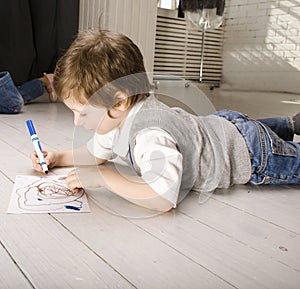 Portrait of little cute boy painting on floor