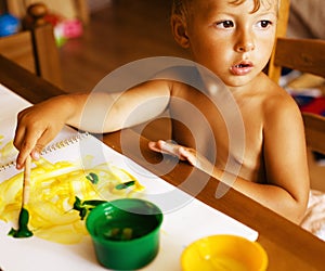 Portrait of little cute boy painting at home