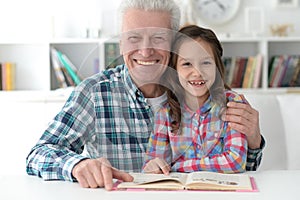 Portrait of little cute girl with grandfather reading book