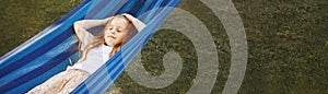 portrait of a little cute girl with long hair resting on a hammock in the garden and smiling