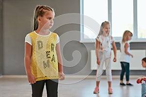 Portrait of a little cute girl looking away while having a choreography class. Group of children standing in the dance
