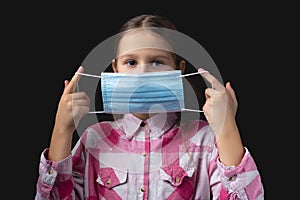 Portrait of a little cute girl with a medical mask isolated on black background