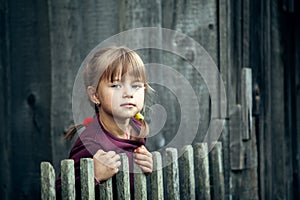 Portrait of little cute girl near vintage rural fence.