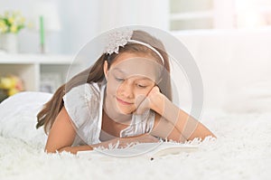 Portrait of little cute girl reading book at home