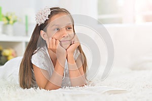 Portrait of little cute girl reading book at home