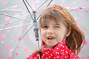 Portrait of little cute girl in red rain coat under the umbrella
