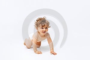 Portrait of little cute toddler boy, baby in diaper crawling isolated over white studio background