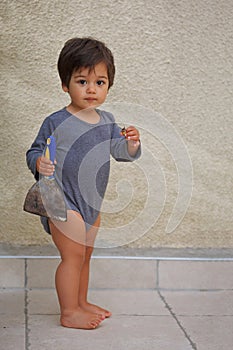 Portrait of a little eastern handsome baby boy playing outdoor with tool spatula