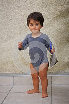 Portrait of a little eastern handsome baby boy playing outdoor with tool spatula