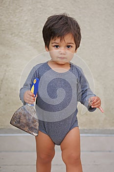 Portrait of a little eastern handsome baby boy playing outdoor with tool spatula