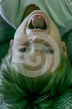 portrait of a little fair-haired cheerful boy lying upside down.