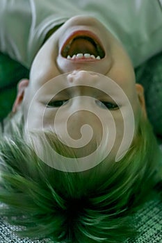 portrait of a little fair-haired cheerful boy lying upside down.