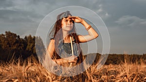 Portrait of Little girl 10-12 years old with long brown hair, walk in a wheat field on a summer evening
