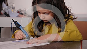 Portrait of a little girl with a 3D pen in her hands at the school of robotics.