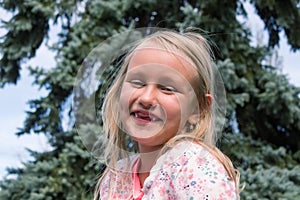 portrait, little girl 6 years old, smiling with an open mouth without milk teeth