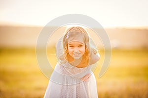 Portrait little girl blonde on at sunset in field