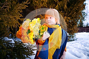 Portrait of Little girl in blue coat, yellow scarf and bouquet of flowers in winter or spring in nature in the