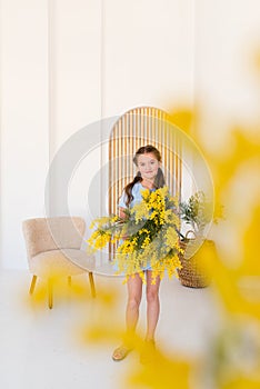 Portrait of a little girl with a bouquet of spring yellow flowers