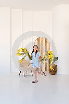 Portrait of a little girl with a bouquet of spring yellow flowers