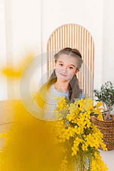 Portrait of a little girl with a bouquet of spring yellow flowers