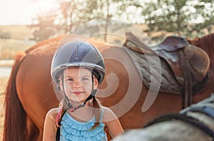 Portrait of little girl and brown Horse. Girl with Helmets