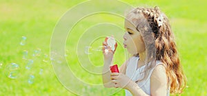 Portrait little girl child blowing soap bubbles in summer day