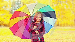 Portrait of little girl child with colorful umbrella in sunny autumn park