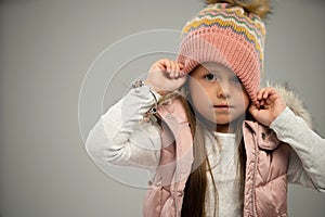 Portrait of little girl, child, posing in warm jacket and hat isolated over white background. Copy space for ad