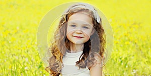 Portrait little girl child in spring field with dandelions flowers