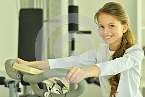 Portrait of little girl doing exercises on exetcise bike in gym