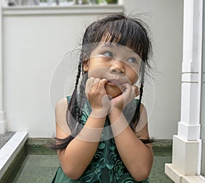 Portrait of a little girl dress nicely smiling hand touching her face looking away. Family, holiday and healthy child concept