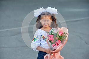Portrait of a little girl elementary school student with a bouquet of flowers .
