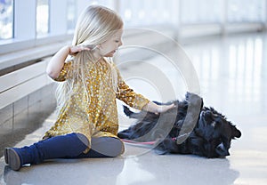 Portrait of little girl enjoying playing with black dog