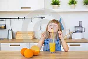 Portrait of a little girl funny drinks a fresh juice on a table