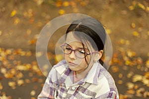 Portrait of a little girl with glasses in the autumn park