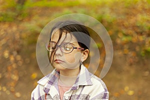 Portrait of a little girl with glasses in the autumn park