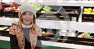 Portrait little girl in a hat and jacket stands against the background of the counter in the store