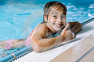 Portrait little girl having fun in indoor swimming-pool