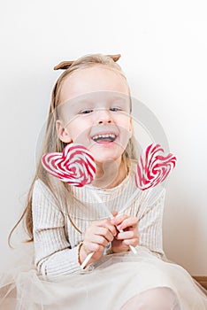 Portrait of little girl with heart candy on a stick, lollipops, Valentine`s day