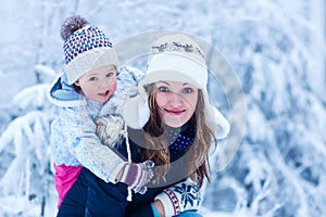 Portrait of a little girl and her mother in winter hat in snow f