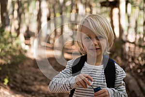 Little girl holding bubble wand in her hand in the forest on a sunny day