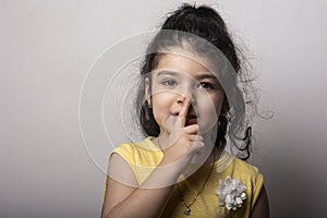 Portrait of little girl keeping secret put finger near lips showing