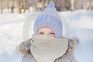 Portrait of little girl in knitted hat and scarf in winter