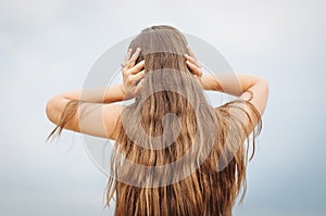 portrait of a little girl with long hair, back, covers her ears with her hands