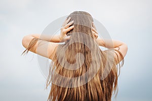 portrait of a little girl with long hair, back, covers her ears with her hands