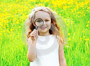 Portrait little girl looking through magnifying glass summer