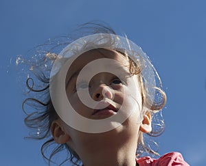 Portrait of a little girl looking up against the sky